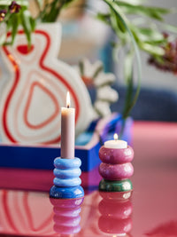 Tana light blue candle holder with a lit taper candle beside a dusty pink stack holding a tea light on a glossy pink table