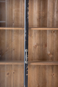 Close-up of the Hazem cabinet's antique brass door handles meeting at the centre of the black distressed frame