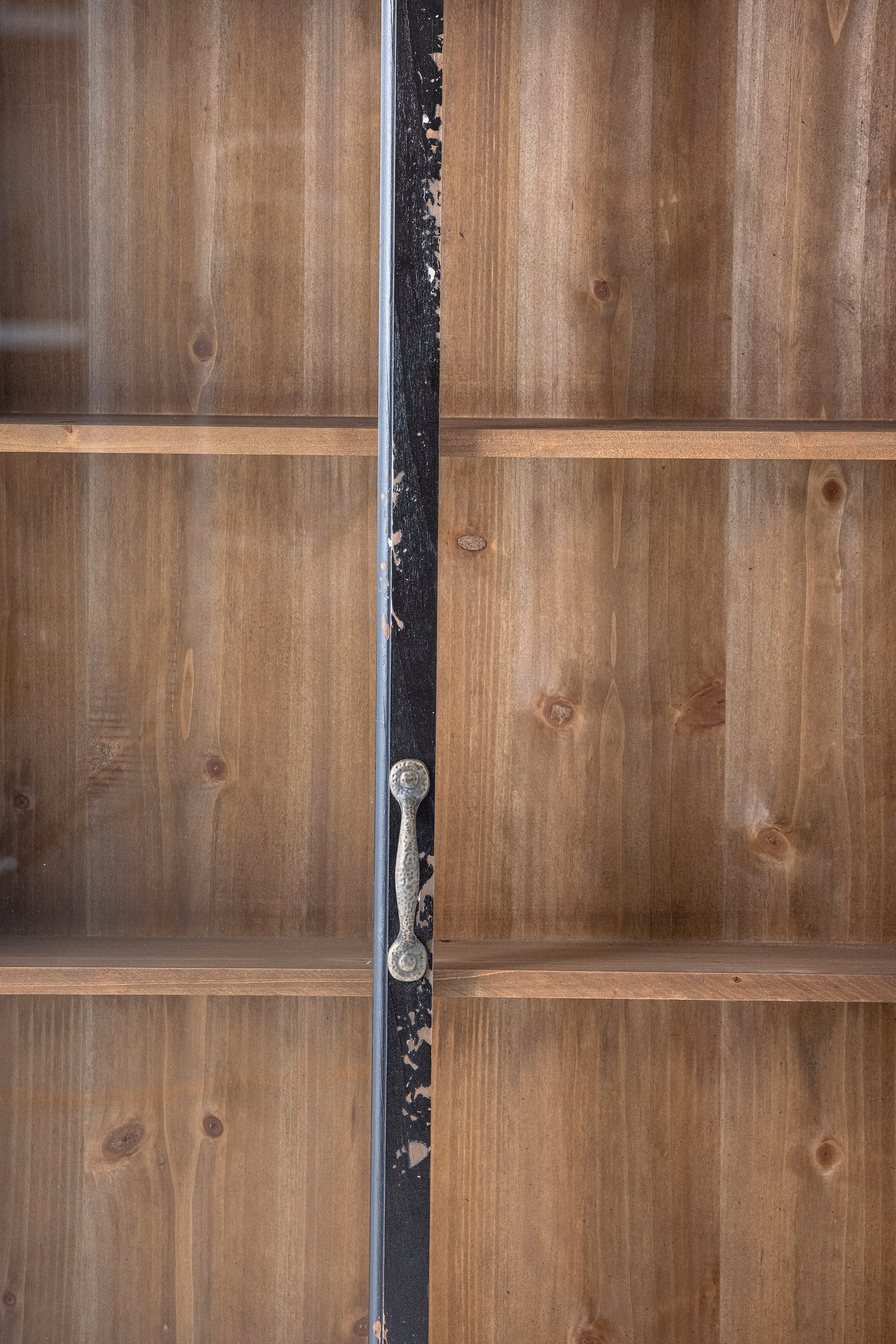 Close-up of the Hazem cabinet's antique brass door handles meeting at the centre of the black distressed frame