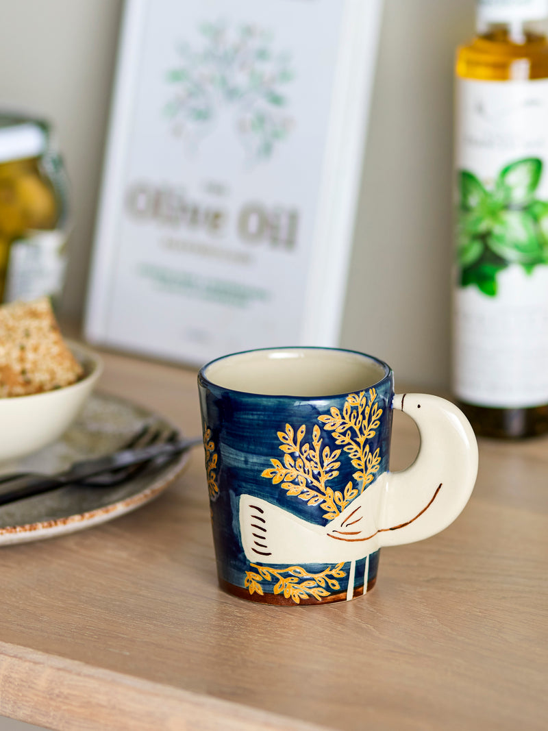 Nature-coloured Bloomingville Hezha cup with raised bird wing handle styled on a kitchen counter beside bread and olive oil.