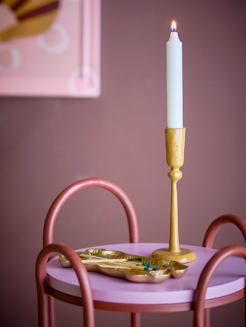 yellow taper candle holder by bloomimgville styled with lit candle on pink table
