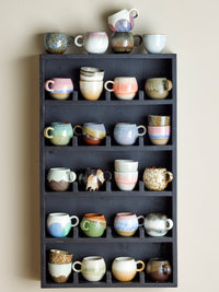 Paula cups and other retro stoneware mugs displayed on a dark shelf, mixed glazes
