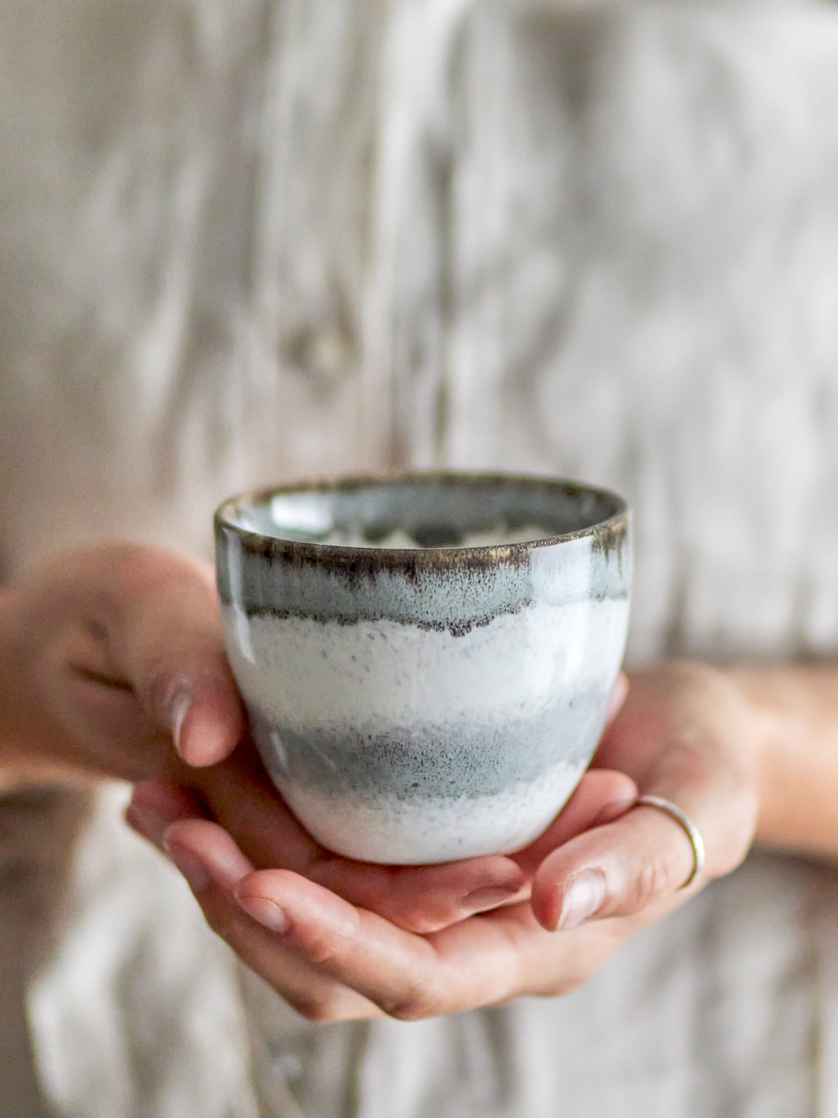 close up of grey bloom­ingville paula cup held in hands showing layered glaze
