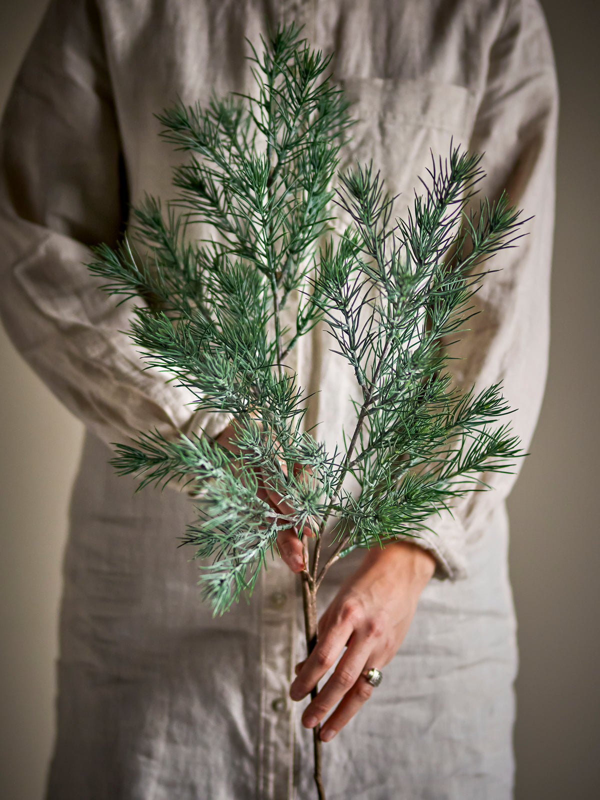 Person in a linen shirt holding the frosted green Pine Stem in both hands