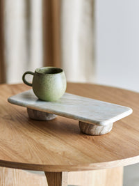 Fatin marble pedestal on a round oak table with a small speckled green stoneware mug resting on top