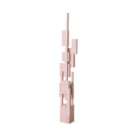 Angled view of the tall soft pink stacked-block wooden sculpture