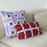 geometric lilac and red hand-tufted cushion by &k Amsterdam styled on a beige sofa
