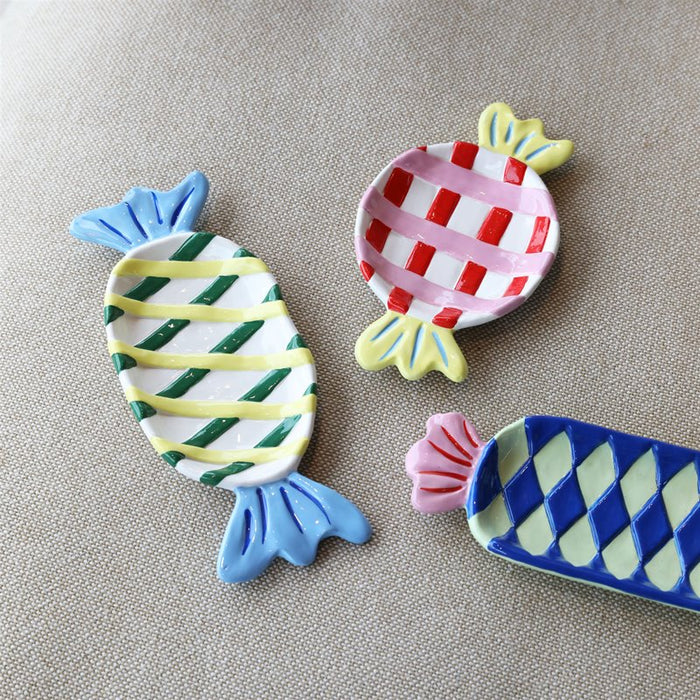 small round candy-shaped ceramic plate in pink and red check with yellow ends

