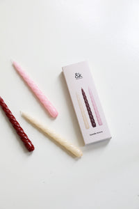 andklevering twisted red candles with gift box flat lay
