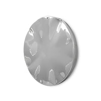 Large chrome wall sculpture with dented surface hung in a modern living room