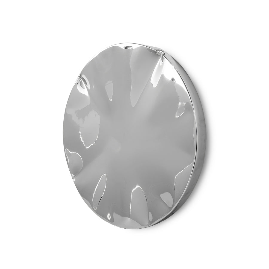 Large chrome wall sculpture with dented surface hung in a modern living room