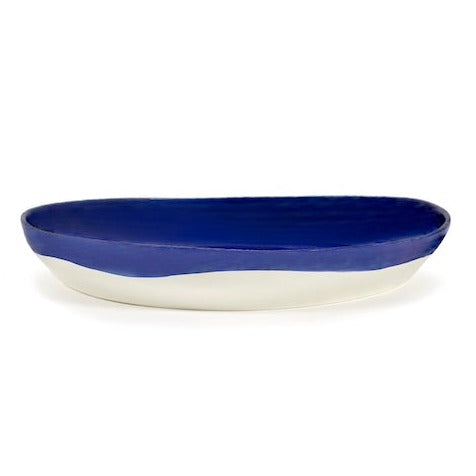 side view of the deep blue serving bowl by ottolenghi and serax where the colour oonly comes down half way on the outside revelaing the white of the ceramic underneath all generously glazed 