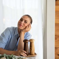 Woman at a table with modern wooden grinder set for kitchen or dining table
