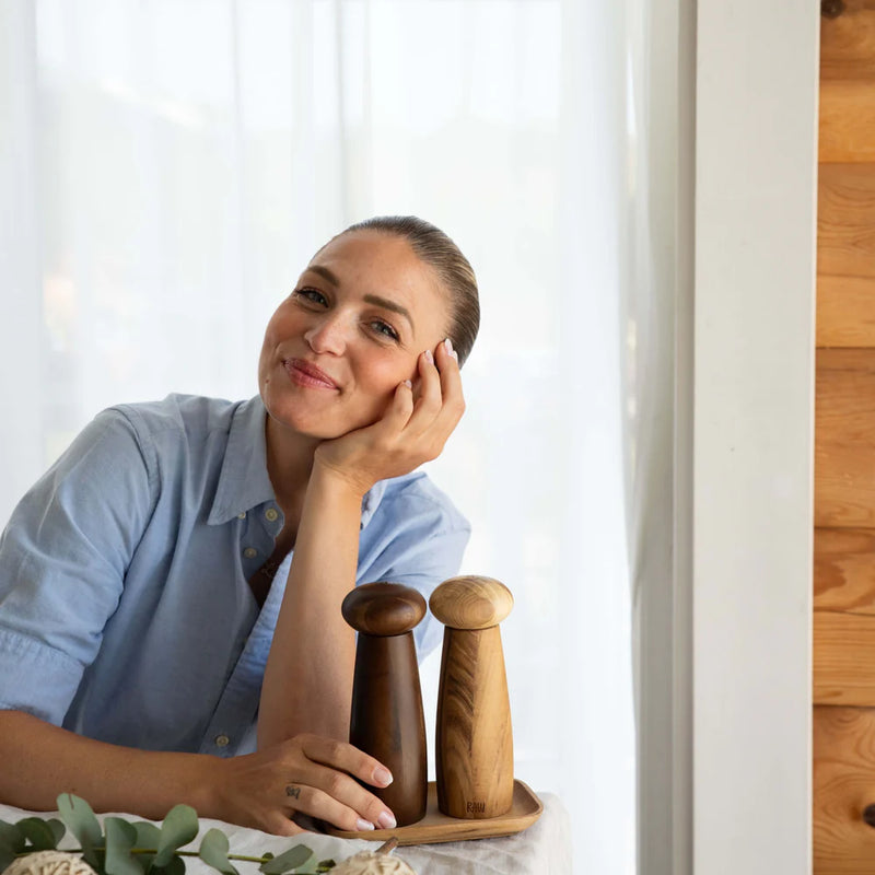 Woman at a table with modern wooden grinder set for kitchen or dining table