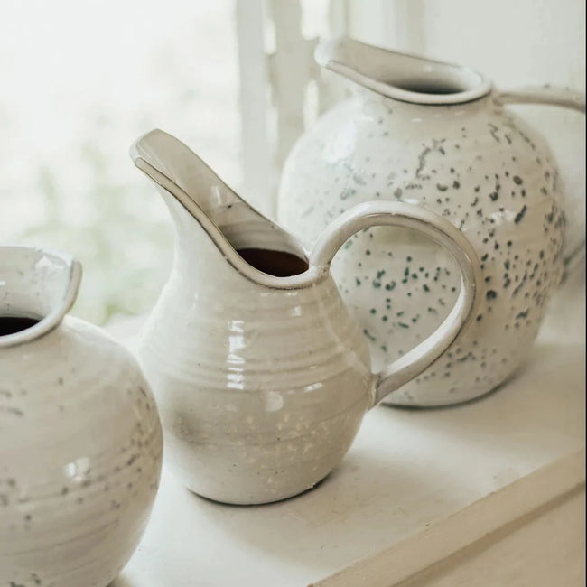 handcrafted clay jugs in a speckled white glaze with different spouts and pourer styles and shapes