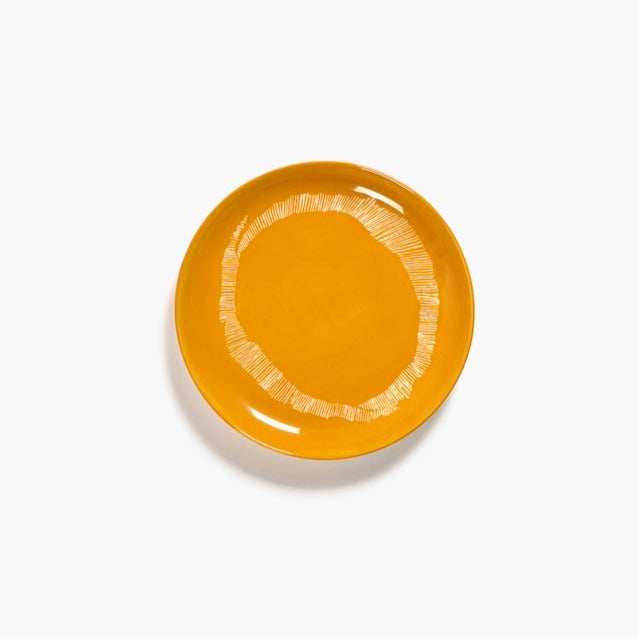 a bright yellow side plate with short thin lines creating an awkward circle aroud the plate in fun bright yellow and white lines