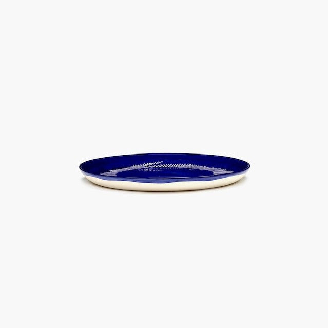 side view of a deep blue plate by ottolenghi and serax showing off its unglazed underside