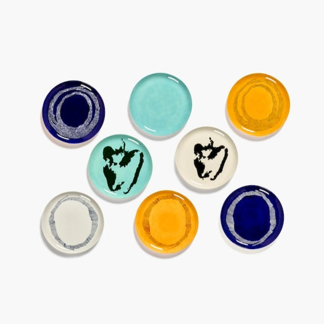 a number of differently styled and coloured dinner plates from ottolenghi with blue azure yellow and white with coloured dots stripes and shapes of bell peppers on them