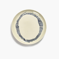 off white dinner plate with black stripes in a circular pattern creating the o of ottolenghi from serax on a dinner plate with a high shine and glaze level