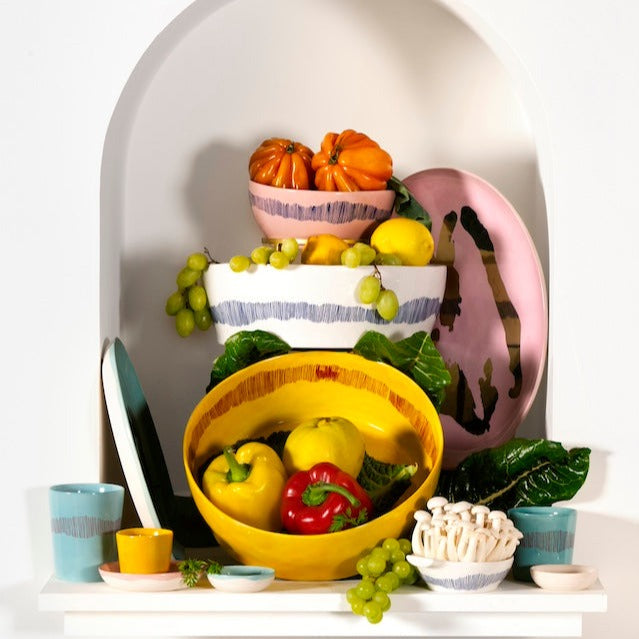 a number of serving plates and dishes displayed together in different colours and styles from azure blue, sunshine yellow, and delicious pink showing that can mix and match different items from the ottolenghi collection and they match perfectly on a single table