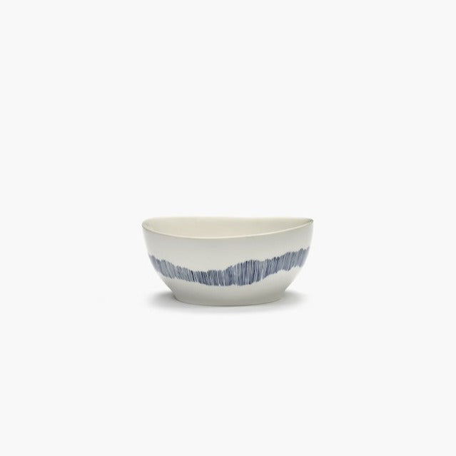 side view of an off white bowl with blue stripes. the stripes are as if done fiine a fine pen or the bristles of a paint brush. high qulaity shine from serax ottolenghi 