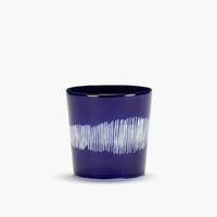 a deep blue cup with white stripes  standing alone revelling in the shine it is getting from teh quality craftsmanship of serax showing off its ottolenghi design on this simple shape of coffee mug