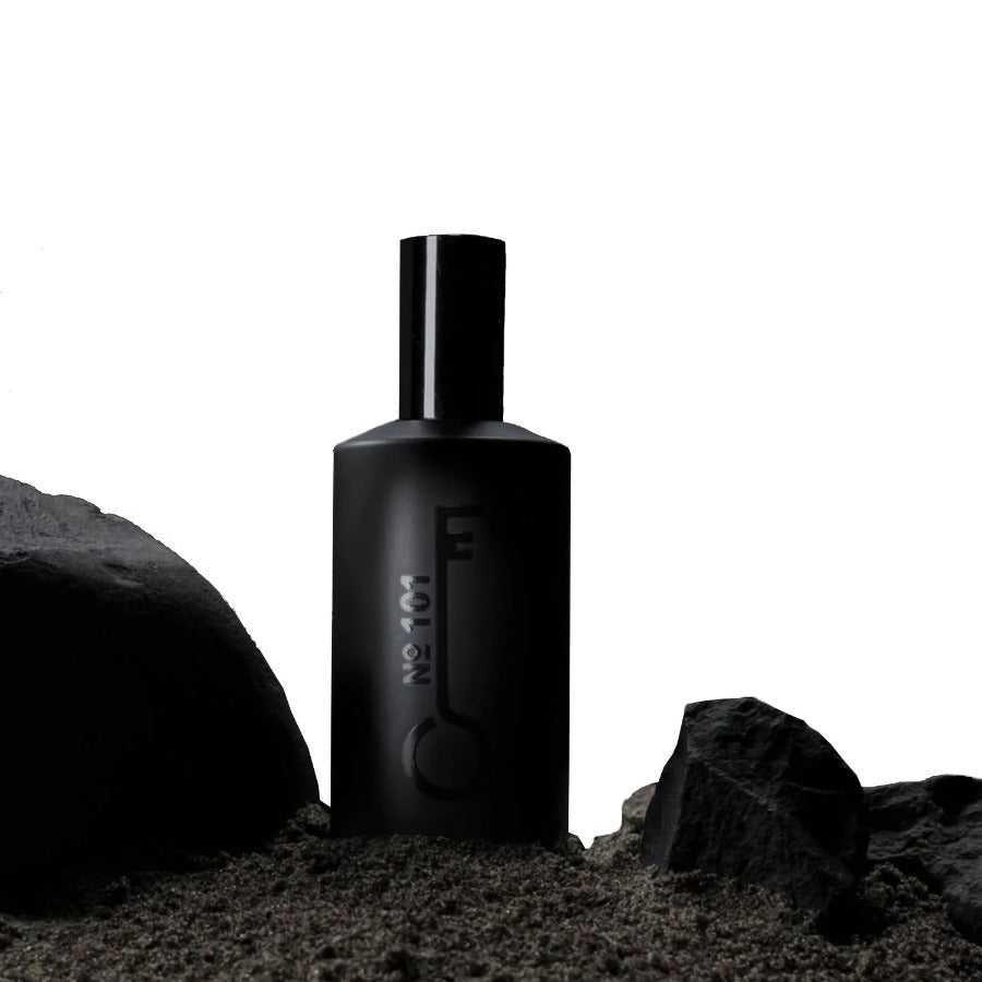 black bottle of fischersund no. 101 fragrance that was hand filled and no sits among black rocks