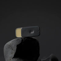 hand finished tin of solid fragrance number 66 by fischersund stood on a black rock