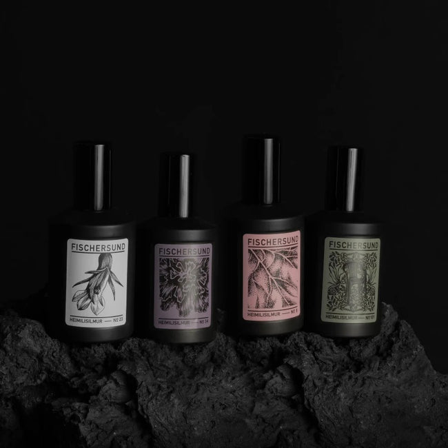 4 black bottles of fischersund home spray scent each with their own particular hand designed art work attached depicting ingredients inside to set a mood and feeling with pink green purple and black and white