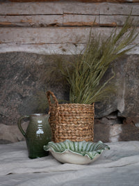 Green terracotta bowl with natural decor and dried grass