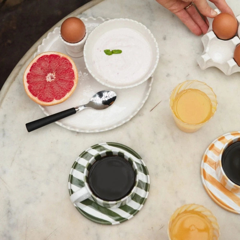 table set for breakfast with striped tea cups and striped coffee mugs on matching saucers in a fun nordic style