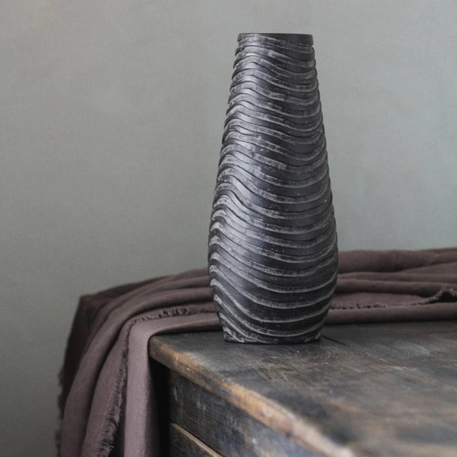 handmade in india this elegant cone shaped black decorative vase has waves running around it revealing many colours of dark browns and black complimenting the black stained dresser that it is seated on