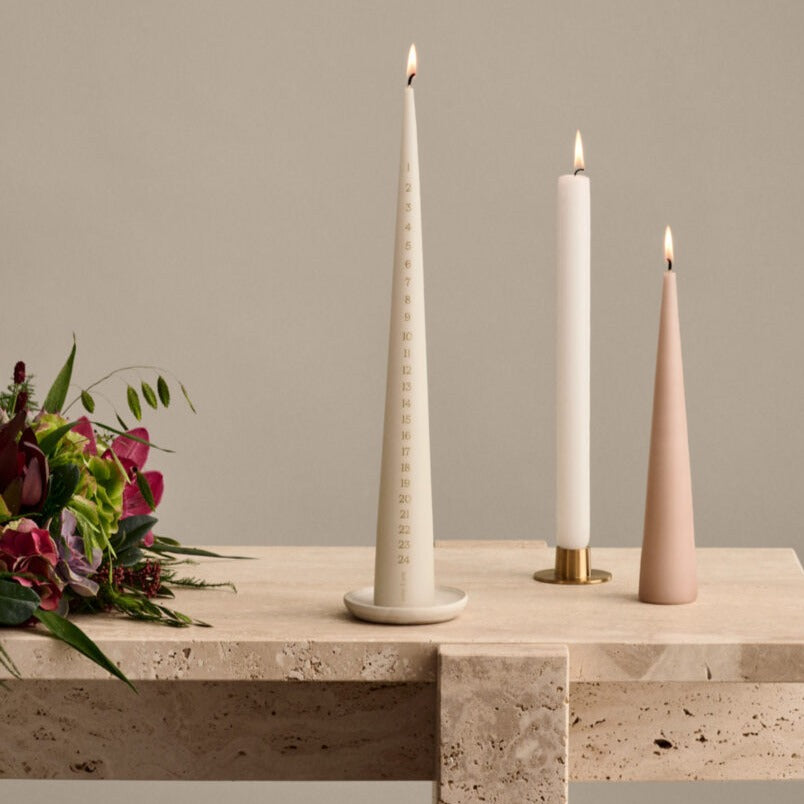 Both cone and coloumn candles in holders on a light beige marble table