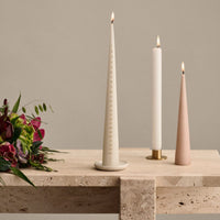 Both cone and coloumn candles in holders on a light beige marble table