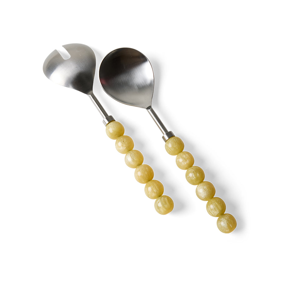 Lemon salad servers laid diagonally on a white background, showing the bead-style resin handles in a soft buttery yellow