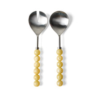 Lemon salad servers by HKLIVING on a white background, showing the stainless steel heads (one slotted, one solid) and pale lemon-yellow bead-style resin handles