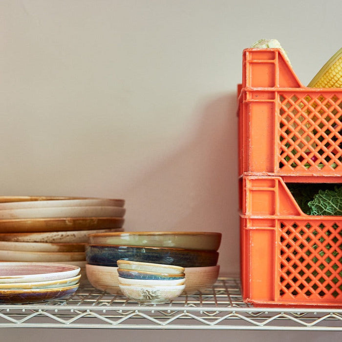 orange crates of fresh veg like corn cobs and cabages sat on a wire shelf with mixed coloured and styles of hkliving tableware