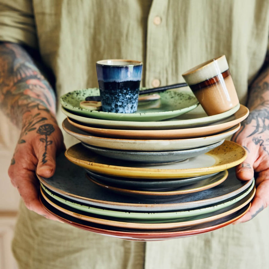 member of the the north home team holding a stack of plates cups and mugs from the hkliving collections