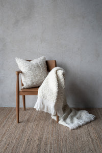 Cosy throw layered with matching cushion in Nordic setting