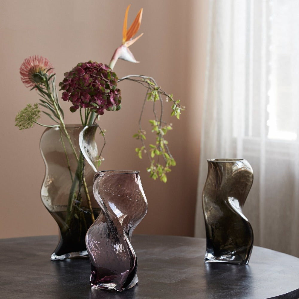 wavey angular vases on a table with flowers and plants 