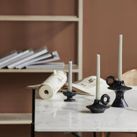 set of black iron candle holders with half burned white taper candles on a white marble table top