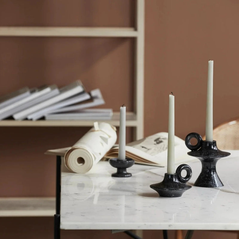 set of black iron candle holders with half burned white taper candles on a white marble table top