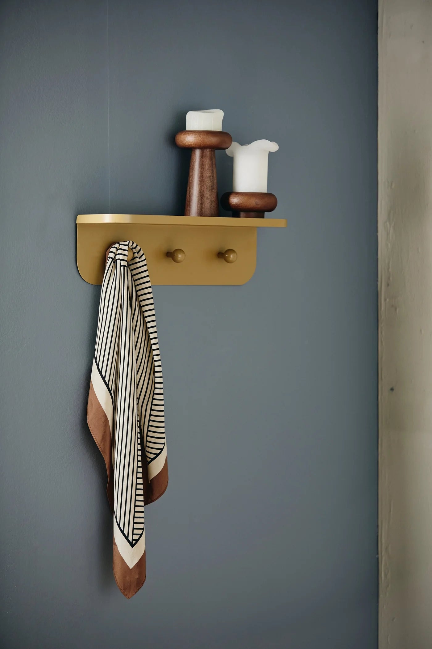 BAWE candle holder in mango wood by Nordal styled on a wall shelf with a candle and scarf