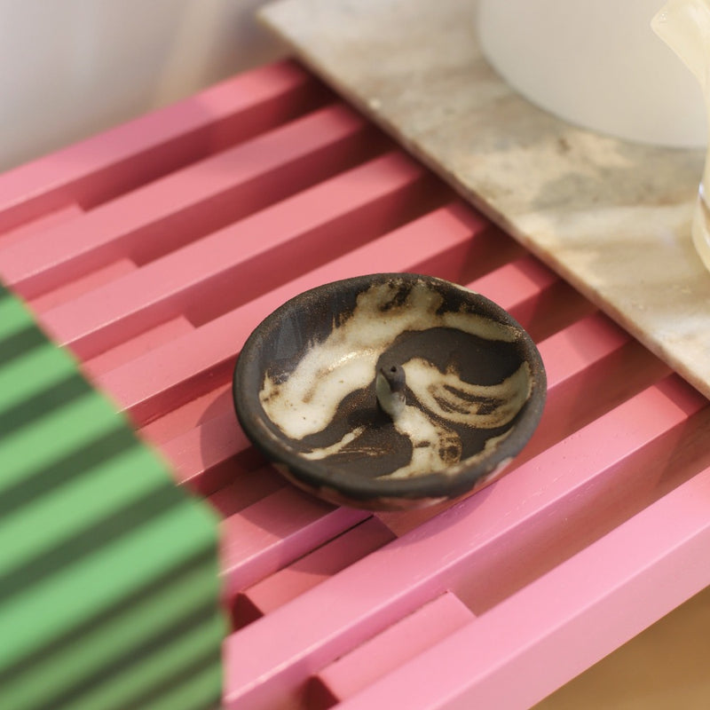 handcrafted bowl incense stick holder by l s ceramics and north home with wisps of smokey white on a pink slatted bench