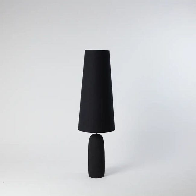 tall standing black lamp with a gold lined lampshade standing tall and elegant with a slight cone shape narrowing to the top of the lamp from nordic interior home design house olsson and jensen