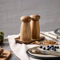 Wooden Aida salt and pepper grinders on a table with plates and cutlery.