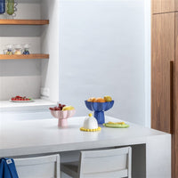 pink stoneware wavy bowl styled on a modern kitchen island filled with fruit
