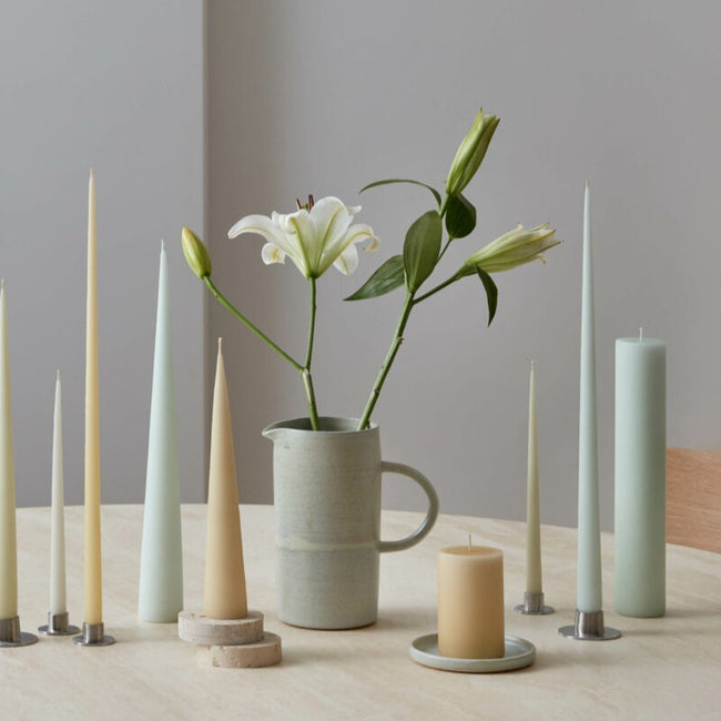 Selection of muted toned candles surrounding a lilly