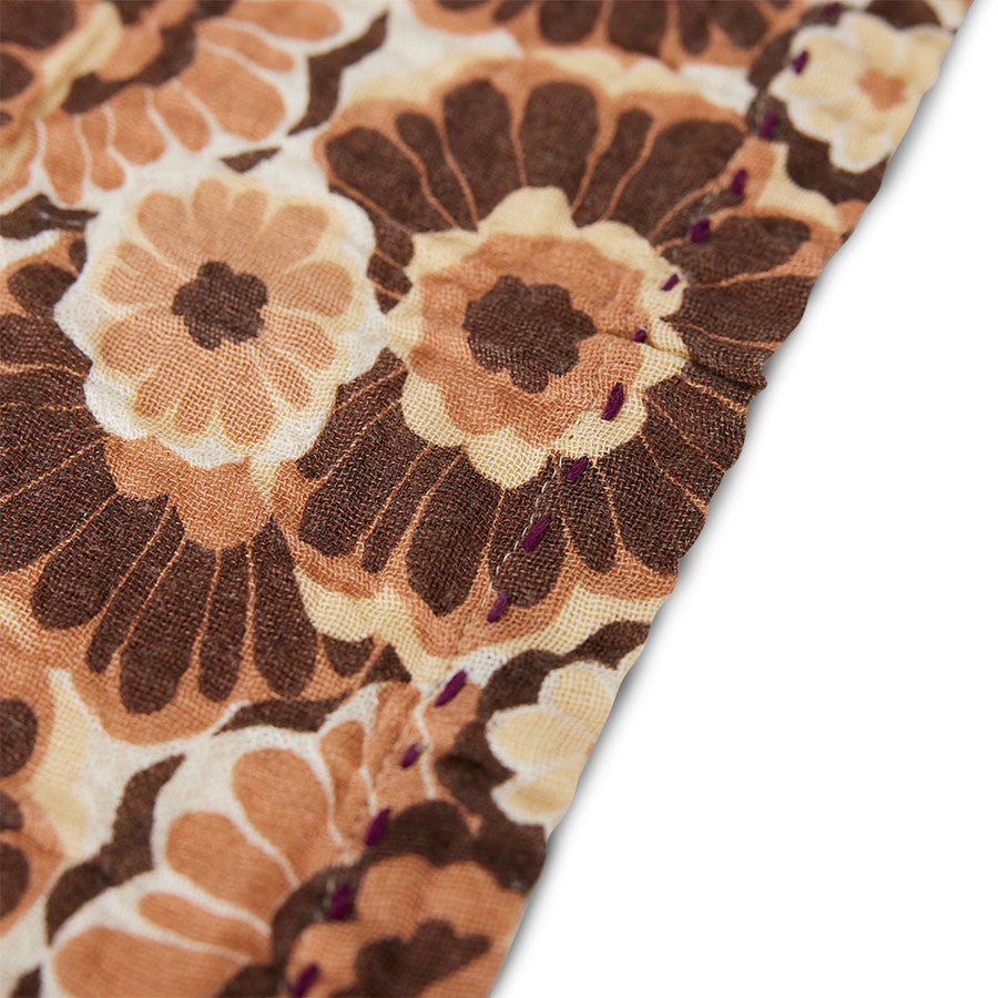 close up of a floral design cloth napkin in browns, orange, yellow from hk living design house