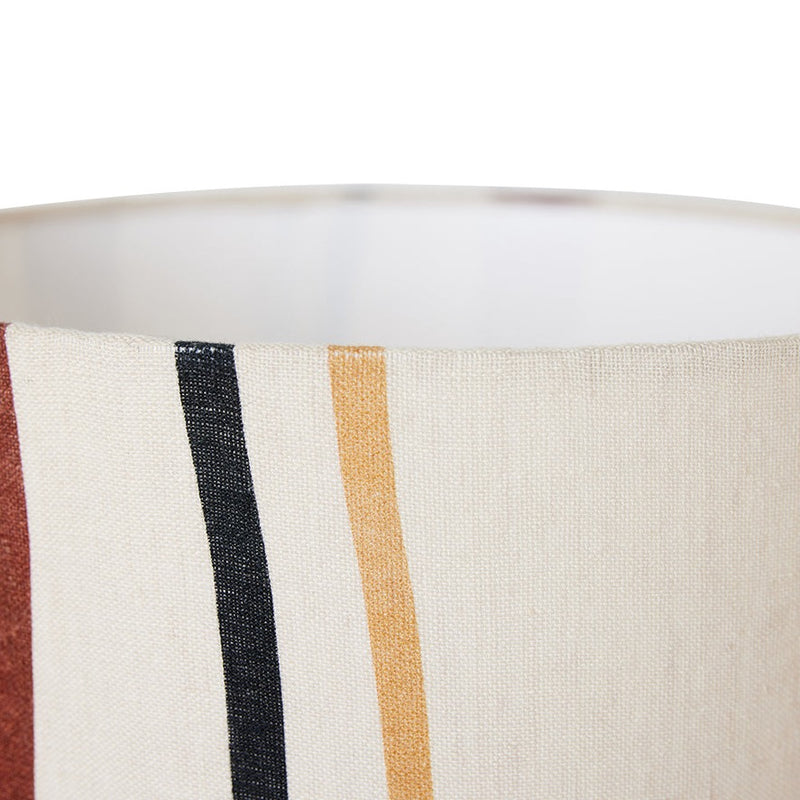 close up of the top of the lamp shade showing the slightly yellow, off white of the overall colour and the top of the curving stripes with red, black, and yellow